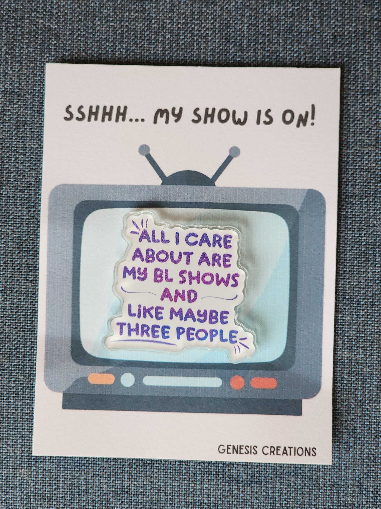 Card with a retro TV graphic and humorous text about a show, on a textured surface.
