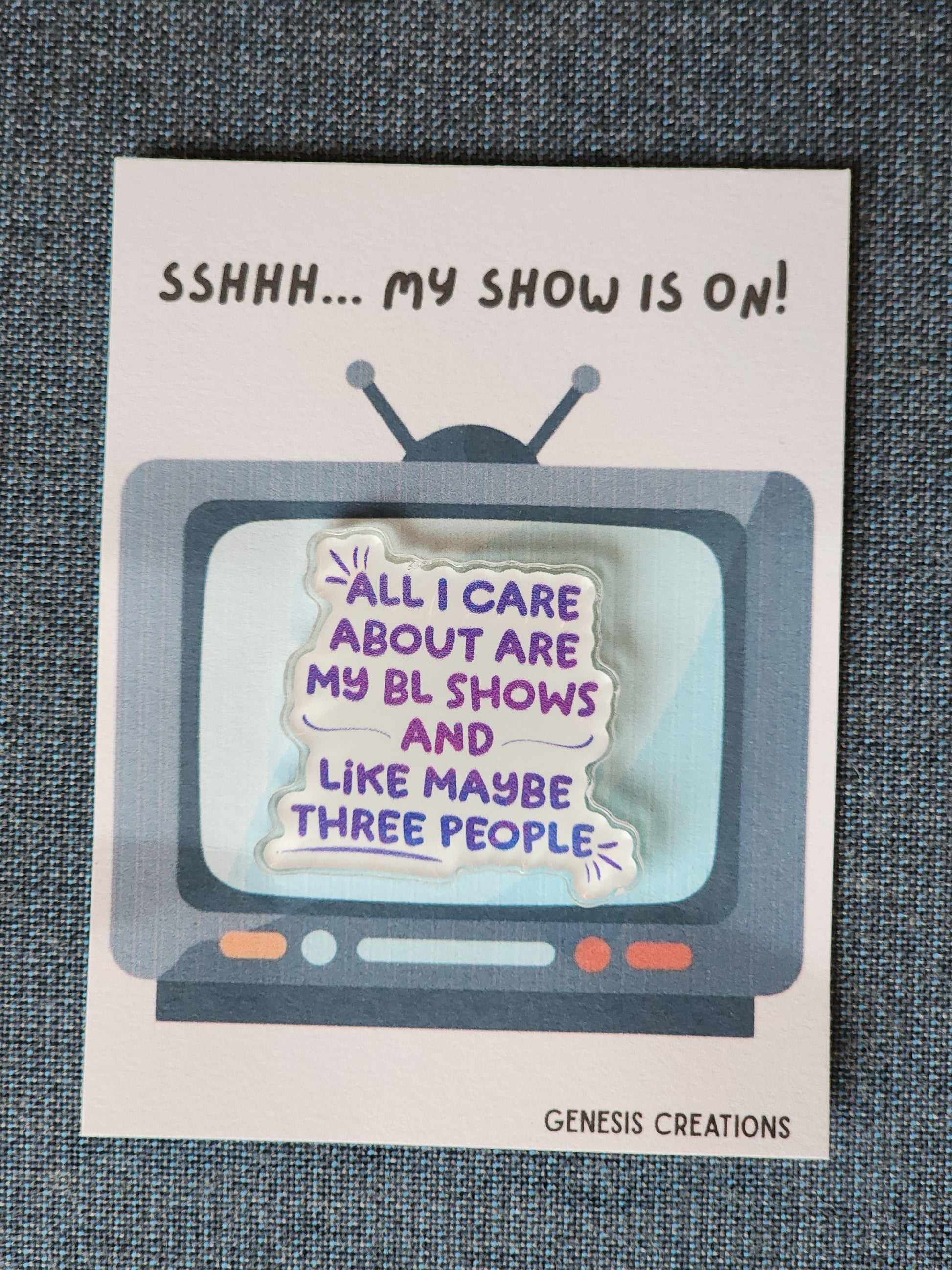 Card with a retro TV graphic and humorous text about a show, on a textured surface.