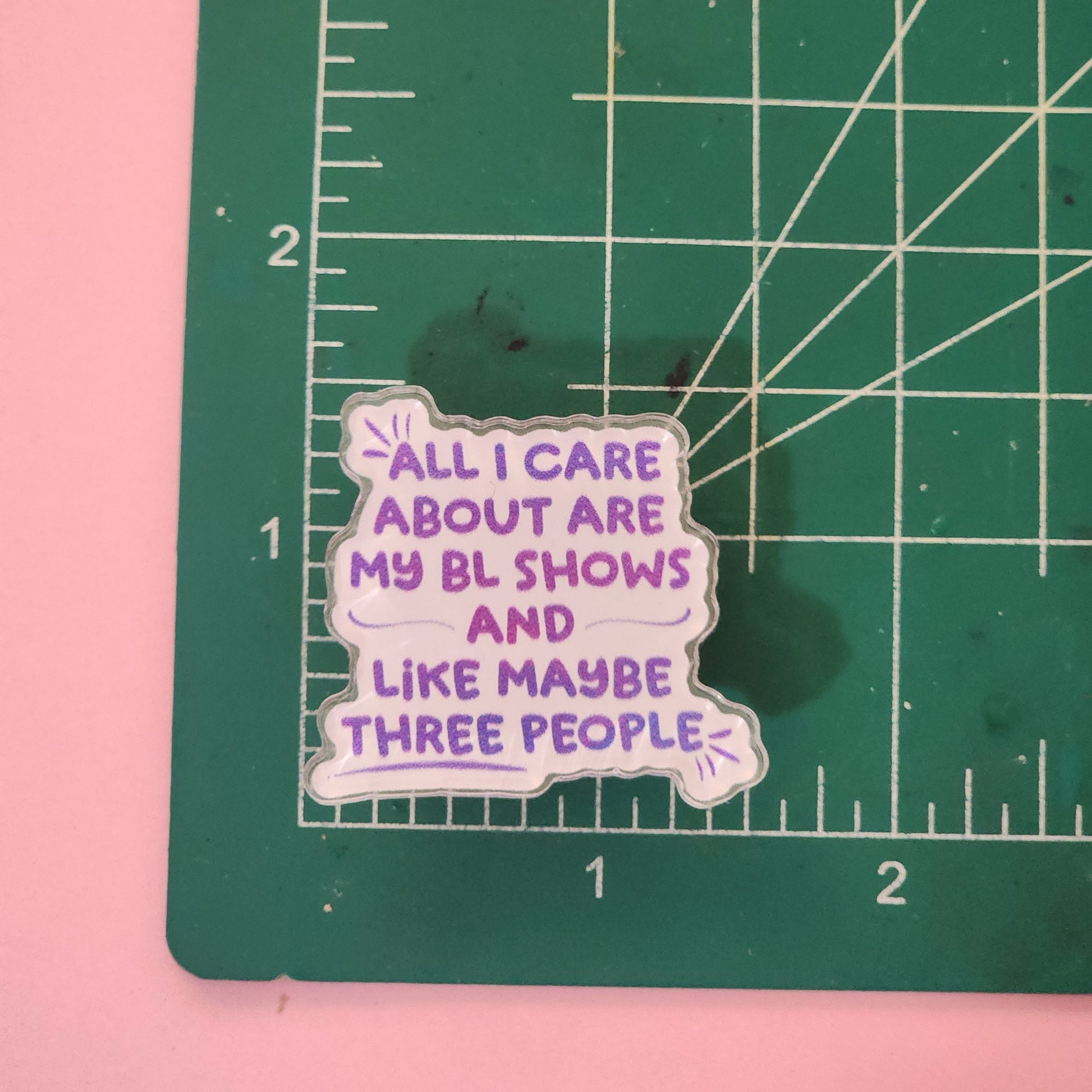 Acrylic pin with text on a green cutting mat with ruler