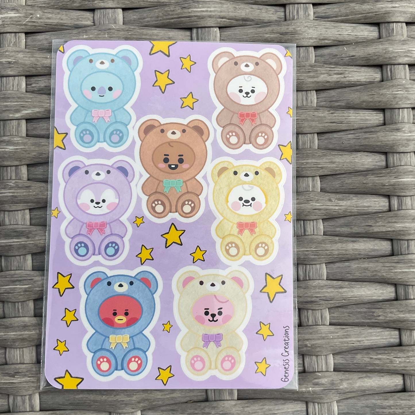 Sheet of colorful bear stickers on a purple background with yellow stars, placed on a woven surface.